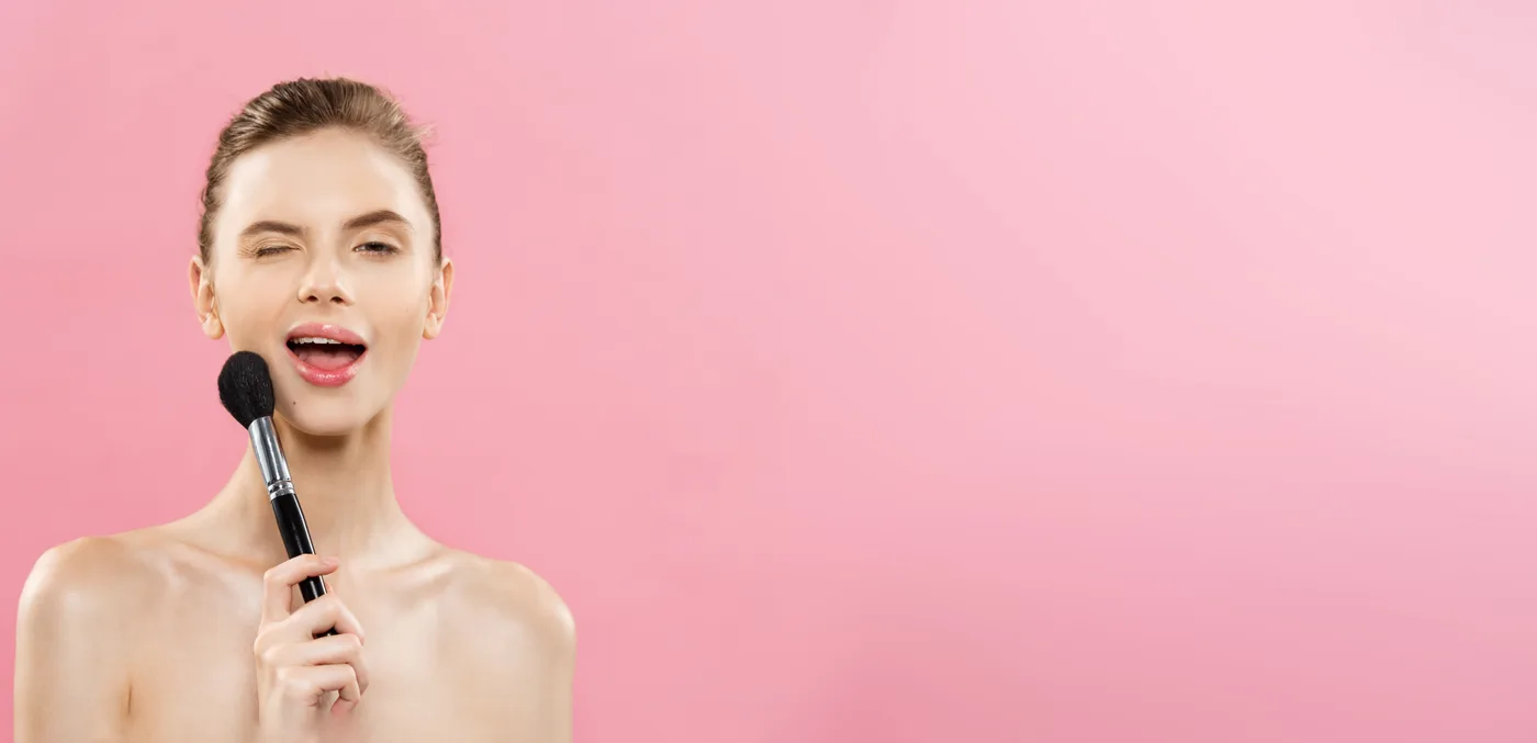 Modelka z pędzlem do makijażu na różowym tle